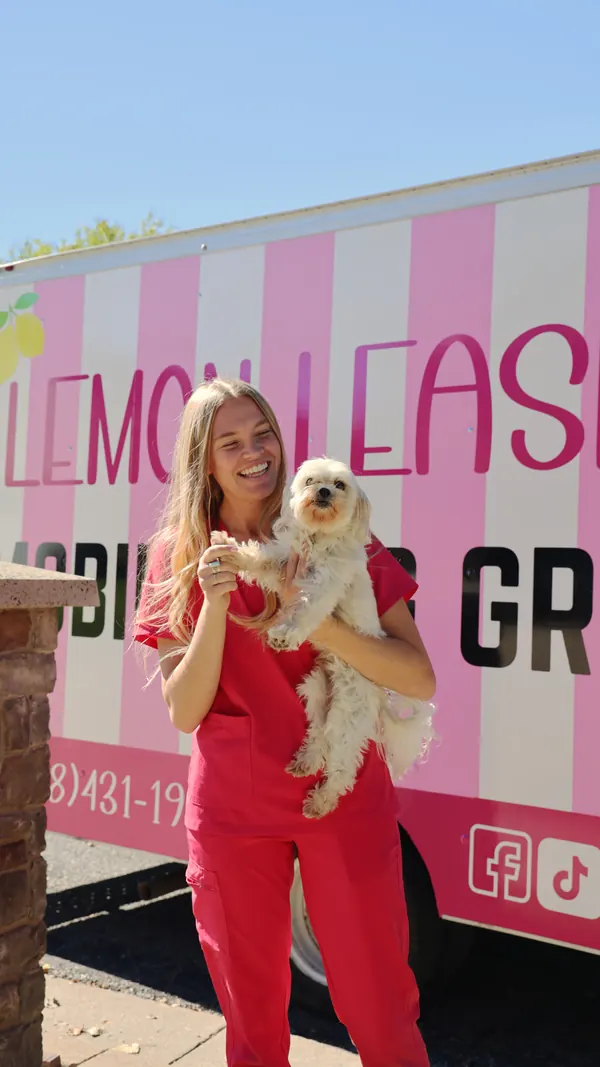 Camrie holding a small white dog in front of the truck